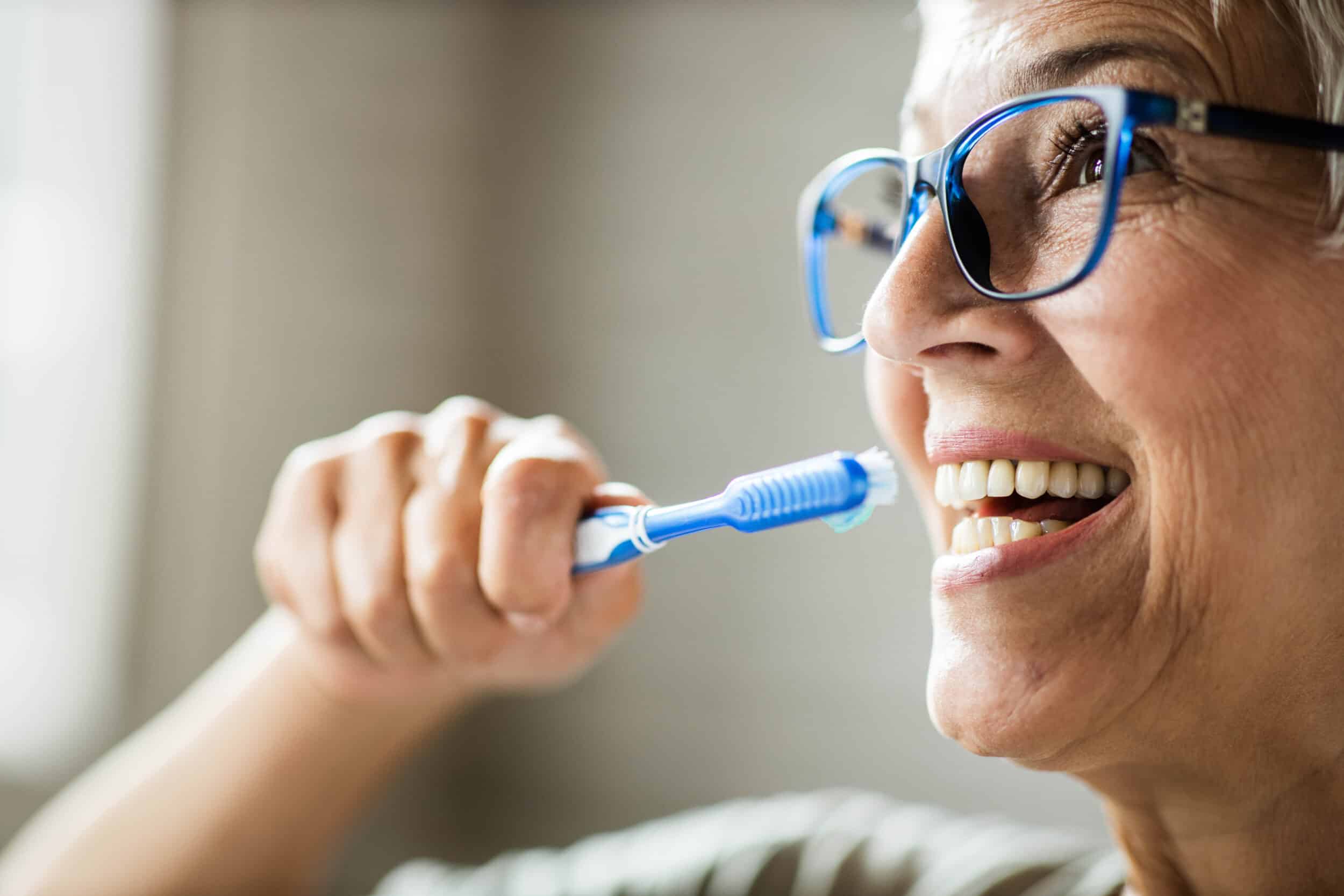 Close up of happy senior woman brushing her teeth.